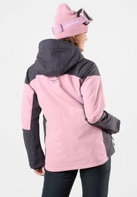 Eine zweifarbige, wasserdichte Jacke in Pink und Dunkelgrau, mit Kapuze, einem Logo auf dem Rücken und Seitentaschen. Glatte Textur mit modernem Schnitt.