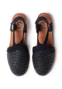Zapatos de cuero trenzado negros con correas ajustables, suela plana y plantilla marrón. Incluyen un detalle de borde trenzado.