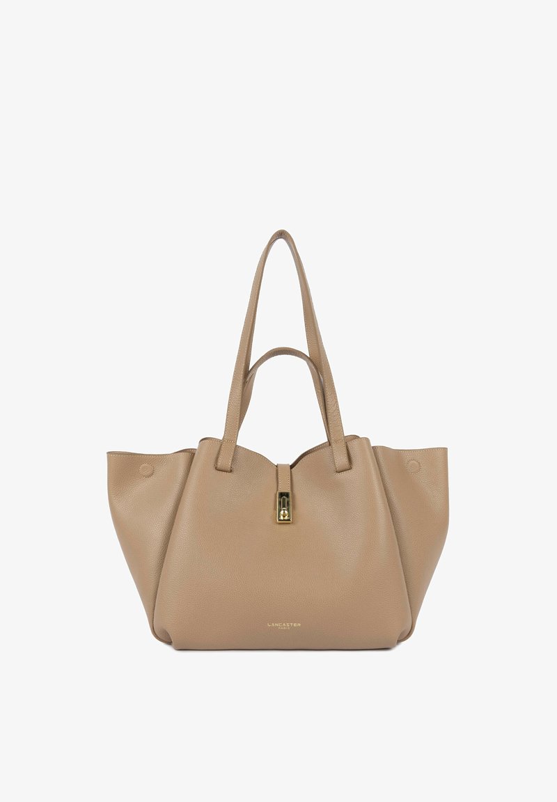 Sac fourre-tout en cuir beige avec deux bretelles d'épaule, une fermeture éclair dorée et une surface subtilement texturée. Présente un design minimaliste.