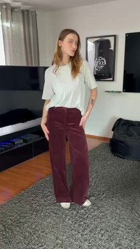 Tricou supradimensionat de culoare gri deschis, asortat cu pantaloni evazați din catifea cord de culoare burgundy și pantofi albi. Textură moale, croială lejeră și siluetă neutră.