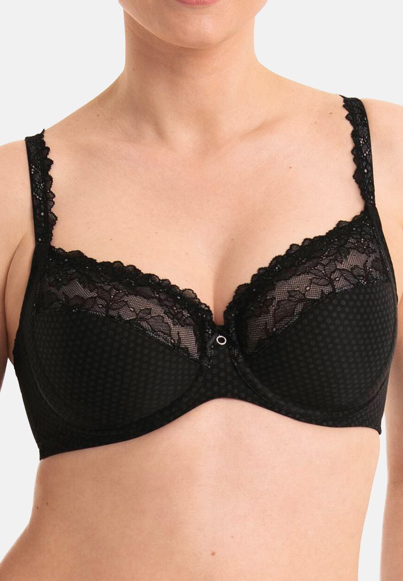 Reggiseno nero con motivo a pois, rifiniture in pizzo lungo la parte superiore e spalline regolabili. Supporto con ferretto e chiusura centrale.