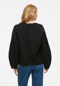 Must have suure oversize-sviiter, millel on langevad õlgade õmblused ja ümar kaelus. Kombineeritud siniste denimiste teksadega. Sile tekstuur, lihtne disain, nähtavad mustrid puuduvad.