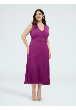 Femme portant une robe midi plissée violette sans manches avec un décolleté en V et des sandales beiges à talons, debout et souriante sur un fond uni.