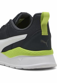 Baskets en maille noire avec des accents blancs et vert lime. Elles comprennent un col rembourré, une semelle texturée et un logo Puma au niveau du talon.