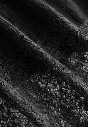 Mustmustest erinevate lillemusteritega must pitskangas, millel on tekstuurne pind ja peen detail, kihtides siledale taustale.