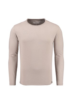 Camisa de manga larga en beige claro, hecha de tela suave. Presenta un escote redondeado y una textura lisa, con un detalle de costura mínimo.