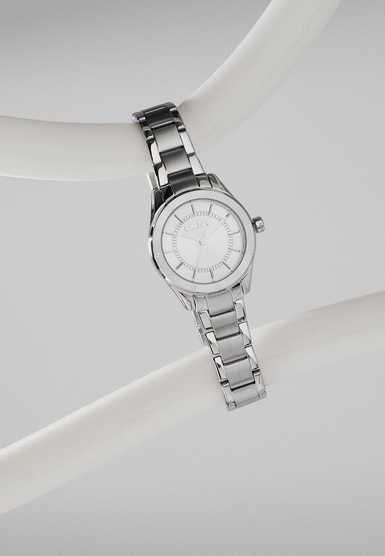 Silberne Edelstahl-Uhr mit rundem Zifferblatt, minimalistisches weißes Ziffernblatt und gravierte Stundenmarkierungen. An einem Gliederarmband befestigt.
