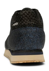 Baskets noires avec une texture bleue pailletée, un accent en cuir de serpent sur le talon et une semelle en caoutchouc de couleur claire avec un relief.