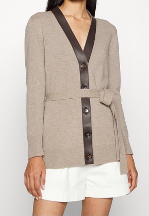 Cardigan en tricot beige avec un décolleté en V profond et des finitions en simili cuir marron. Il présente une ceinture à la taille et des boutons marron sur le devant.