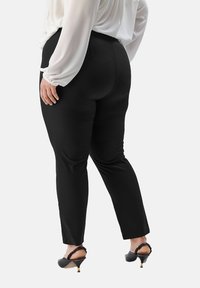 Zwarte broek met een gladde textuur en een op maat gemaakte pasvorm, met een middelhoge taille en een enkellange snit. Draag met een witte blouse en zwarte hakschoenen.