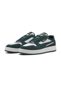 Mørkegrønne ruskinds sneakers med hvide detaljer og en perforeret tå. Har en polstret sål og guld branding på tungen.