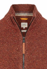 Roter Strickpullover mit hohem Kragen, Reißverschluss und strukturiertem Muster. Mit einem Leder-Reißverschlussanhänger und gestreiftem Innenfutter.