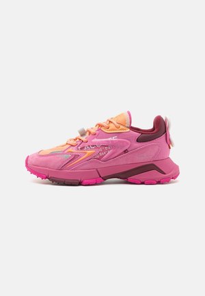 Pink og orange atletik-sneaker med meshpaneler, tyk sål og snørelukning, vist fra siden på en ensfarvet hvid baggrund.