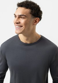 Donkergrijze lange mouw-shirt gemaakt van zachte stof, met een ronde hals en een gladde textuur. Eenvoudig ontwerp zonder zichtbare logo's of patronen.