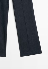 Ciemnoniebieskie dżinsy o prostym kroju, z gładką fakturą i kontrastującymi szwami wzdłuż szwów.