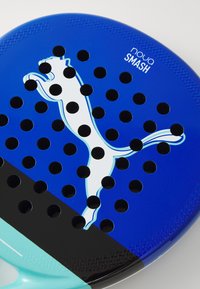 Blaues Paddel mit runden Löchern, das ein Design einer weißen Katze und den Text "nova SMASH" zeigt. Glatte Oberfläche mit aqua- und schwarzen Akzenten.