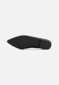 Zapato de tacón alto negro con punta afilada, textura suave y suela de goma plana. Logotipo "paul green" grabado en el tacón.