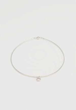 Srebrna lančana ogrlica s jednim okruglim prozirnim draguljem u privjesku, postavljena na jednobojnoj bijeloj pozadini.