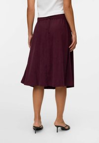 Jupe bourgogne mi-longue en tissu doux avec un design fluide, taille élastique et texture lisse. Présente un ourlet simple.