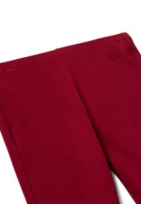 Rote, dehnbare Leggings mit glatter Textur und elastischem Bund. Mit einem kleinen, gestickten Logo in der Nähe des Bundes.