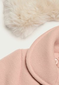 Lys rosa uldfrakke med en struktureret overflade, der har en stor krave og en knaplukning. Ovenfor en blød, fluffy hvid pelsdetalje.