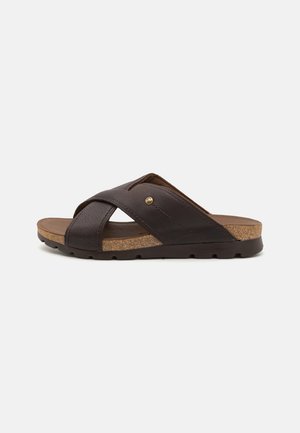 Braune Ledersandalen mit Korksohle, ausgestattet mit übereinander laufenden Riemen und einer strukturierten Oberfläche. Die Sohle hat ein gemustertes Profil.