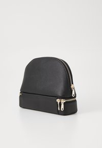 Borsa cosmetica nera strutturata con parte superiore arrotondata e doppie cerniere dorate. Realizzata in materiale testurizzato, presenta una finitura liscia sulla base.
