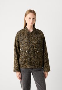 Leopardmønstret jakke i brun og sort, med knaplukning fortil, to brystlommer og brede ærmer. Textureret stof.