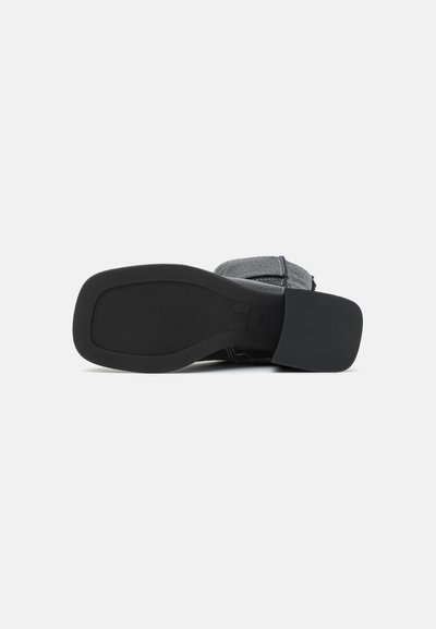 Sola de sapato em borracha preta com grip texturizado, salto ligeiramente elevado e bordas arredondadas. Apresenta uma superfície lisa com costura de destaque mínima.