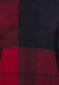 Rot-karierter und marineblauer Pullover aus einer weichen Wollmischung, mit einer strukturierten Oberfläche und diagonalen Mustern sowie einem hohen Kragen.