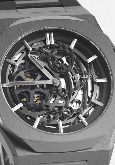 Skelettuhr mit einem grauen Edelstahlgehäuse und -armband. Verfügt über komplexe Innenmechaniken, markante silberne Stundenmarker und ein elegantes Design.