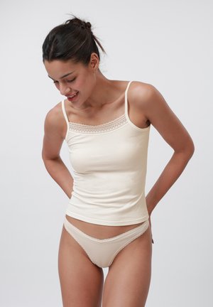 Beige geribbelde tanktop met kantafwerking bij de halslijn, gecombineerd met bijpassende beige onderbroekjes met kantafwerking. Beide artikelen hebben een aansluitend ontwerp.