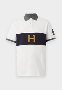 Valkoinen polo-paita, jossa on tummansininen vaakasuora raita, brodeerattu kultainen "H"-logo, harmaa kaulus ja hihasuojukset. Puuvillamateriaali.