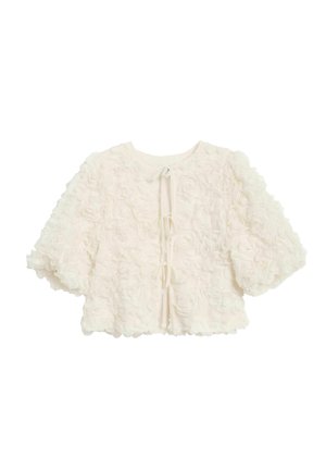 White floral-textured cropped jacket with puffed sleeves, featuring a round neckline and a tie closure at the back. Soft and three-dimensional design.