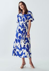 Mėlynas ir baltas gėlių rašto mygtukinis suknelė su trumpomis pūstomis rankovėmis, diržu liemeniui ir kulkšnies ilgio dizainu. Lygus audinio paviršius.