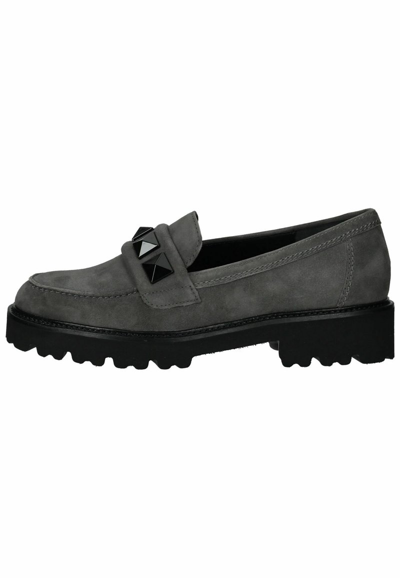 Mocasines de ante gris con una suela de goma negra gruesa, que presentan tachuelas piramidales negras en la correa y sutiles detalles de costura.