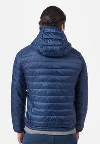 Giacca a vento blu navy con cappuccio posteriore, design trapuntato e orlo elastico. Materiale sintetico liscio con una lucentezza.