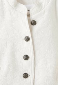 Tissu blanc texturé avec un motif floral subtil et quatre boutons métalliques décoratifs avec un dessin de blason en relief.