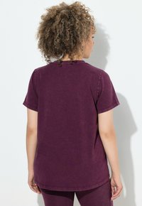 Kurzärmliges, lila Baumwoll-T-Shirt mit Rundhalsausschnitt, geradem Saum und lockerer Passform. Leicht strukturierter Stoff. Keine sichtbaren Logos oder Muster.