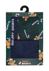 Twee herenboxershorts in maat medium, één effen marineblauw en één donkergroen met prints van zuurstokken en peperkoekmannetjes, verpakt in een feestelijke doos.