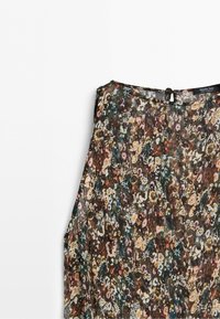 Mouwloze blouse met bloemenpatroon in een mix van donkere en lichte kleuren en een kleine knoopsluiting aan de achterkant van de halslijn.