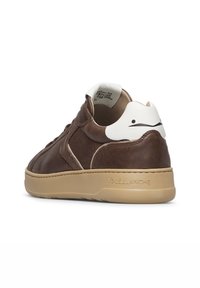 Sneaker in pelle marrone con suola beige, tallone bianco con un volto sorridente minimalista nero, "VOILE BLANCHE" impresso sul lato della suola.