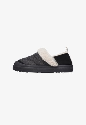 Chaussure noire à enfiler avec un dessus texturé, dotée d'un col blanc en peluche et d'une semelle en caoutchouc. Le design est minimaliste sans quincaillerie visible.
