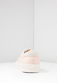 Světle růžové tenisky s měkkou semišovou patou a bílou gumovou podrážkou. Vyznačují se čistými liniemi a minimalistickým designem bez viditelných vzorů.