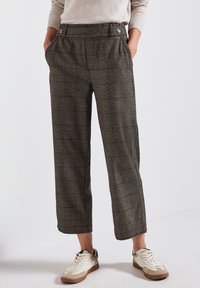 Grå rutiga vida byxor med hög midja, två sidofickor och två knappar, kombinerat med vita och beige sneakers.