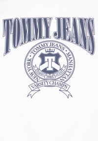 T-shirt bianco con una grafica audace in navy che include "TOMMY JEANS" e un emblema circolare con una "T" e il testo "VARSITY CHAMPS".