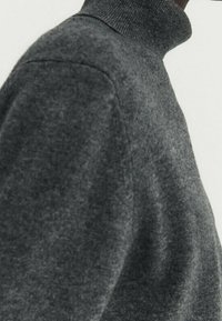 Grauer Wollrollkragenpullover mit taillierter Form. Der Stoff hat eine strukturierte Oberfläche und gerippte Details am Kragen.