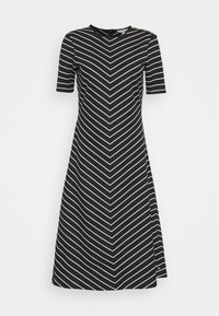 Schwarz Kleid mit einem Zickzackmuster in Weiß, kurzen Ärmeln, rundem Ausschnitt und einem seitlichen Reißverschluss. Mit Hardware an der Schulter akzentuiert.