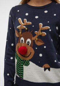 Knit sweater featuring a reindeer with a red pom-pom nose, antlers adorned with bells, and a green striped scarf on a navy background.