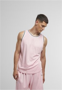 Haut de sport sans manches rose avec un col rond, mettant en valeur des détails noirs contrastants au niveau de l'encolure et des emmanchures, fabriqué à partir d'un tissu texturé.